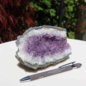 Amethyst Drusen Unikat Nr. 46 auf weißem Tisch, neben Kugelschreiber, ideal zum Kaufen im Online Shop für Energie und Schönheit.