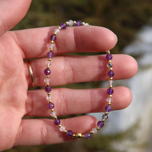 Hand holding a handmade amethyst and tourmaline quartz bracelet with faceted gemstone beads, 17cm length.