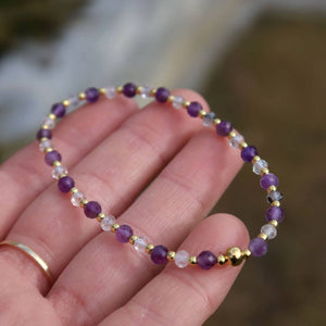 Hand holding a handmade amethyst and tourmaline quartz faceted gemstone bracelet with gold accents, 17cm length.