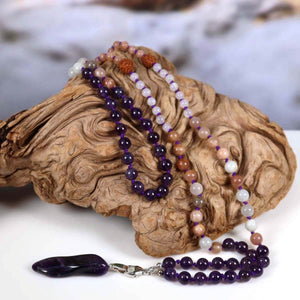 Mala Kette mit Amethyst Anhänger auf Holz, kombiniert mit Mondstein, Labradorit und Rudraksha für Harmonie und Transformation.