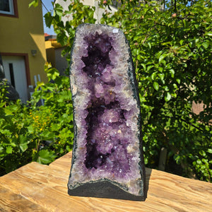 Amethyst Druse – Geode - 52x25x18cm und 23,6kg – Steinwelten OG - Nr. 44 standing on a wooden table in a garden setting