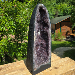 Amethyst Druse – Geode - 57x22x22cm und 28kg – Steinwelten OG - Nr. 64 in a garden setting, ideal for stylish interiors and meditation.