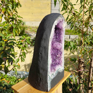 Unique Amethyst geode on display outdoors with vivid purple crystals and natural rough exterior, ideal for home decor and meditation