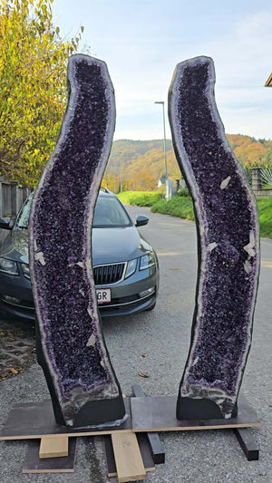 Two large amethyst geode pairs with deep purple crystals displayed outdoors, ideal for luxury decor
