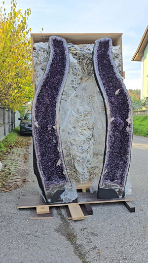 Large amethyst geode pair in a shipping crate, displayed outdoors with intense dark purple crystals visible, ideal for luxury decor.