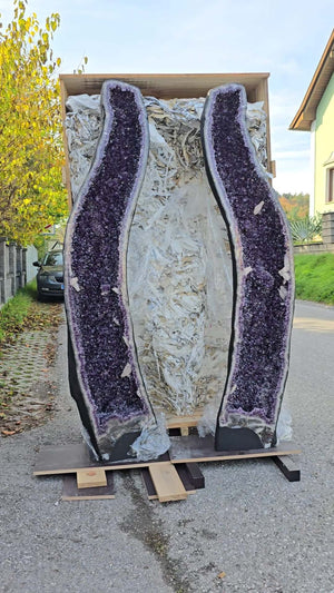 XXL Amethyst geode pairs with intense dark purple crystals, displayed in an open wooden crate on a street.
