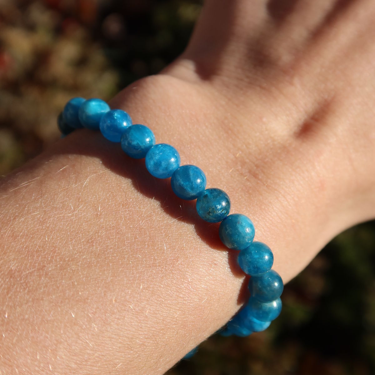Händetragenes Apatit 1A Edelstein Armband - 1 Stück - in Varianten 4-6-8 oder 10mm, zeigt die strahlende blaue Farbe der Perlen.