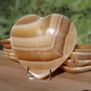 Herzförmige Aragonit-Onyx Schale, 16 cm groß, dekorativer Edelstein aus Marokko auf Holzdisplay. Produkt von Steinwelten Graz.