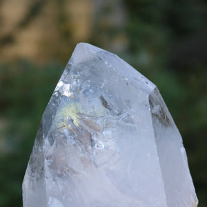 Close-up of polished Bergkristall quartz crystal with natural clarity, highlighting its faceted surfaces against a blurred background.