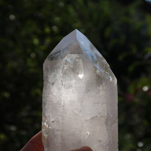 Hand holding a polished quartz crystal point with natural sparkle, perfect for clarity and meditation, from Brazil.