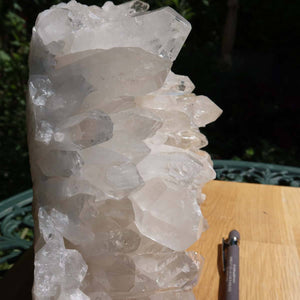 Raw Bergkristall crystal cluster with clear points, 4.8kg, on wooden table. Unique Brazilian piece for clarity and focus.