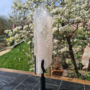 Bergkristall XXL Quarzspitze auf Metallständer im Garten, natürliche Optik, ideal für Yoga-Studios und Meditation.