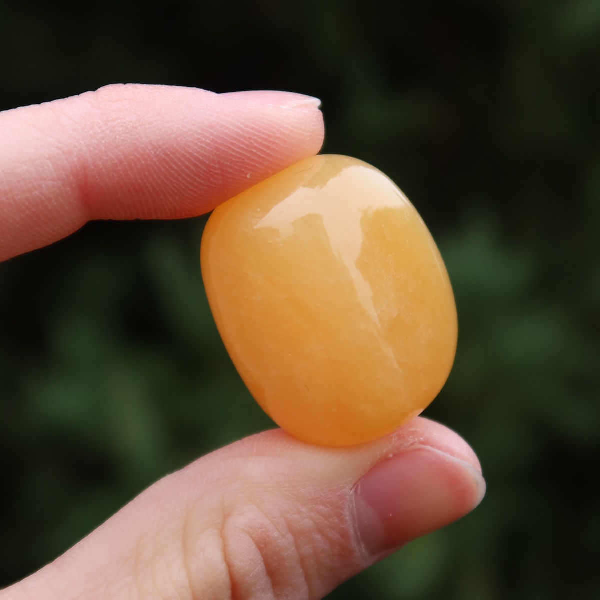 Calcit orange Handschmeichler - Selbstvertrauen und Positivität - Nr. 10 in der Hand, strahlend orange und warm.