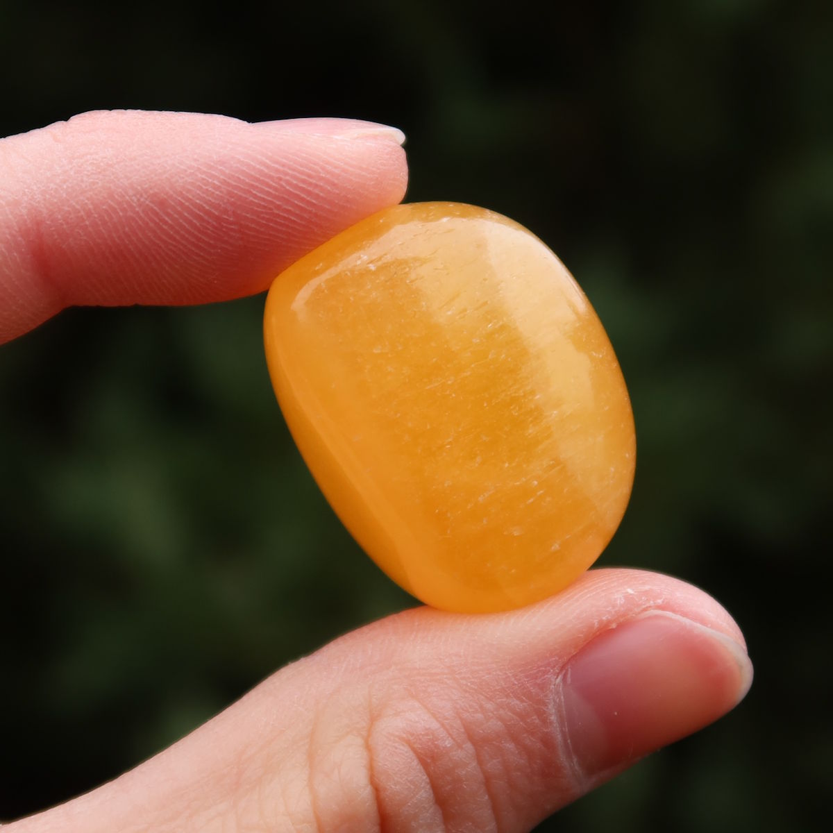 Calcit orange Handschmeichler - Selbstvertrauen und Positivität - Nr. 15, strahlender orangefarbener Stein in Hand.