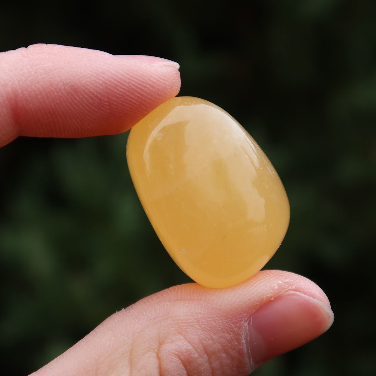 Calcit orange Handschmeichler - Selbstvertrauen und Positivität - Nr. 16 in der Hand, leuchtend gelbe Farbe.