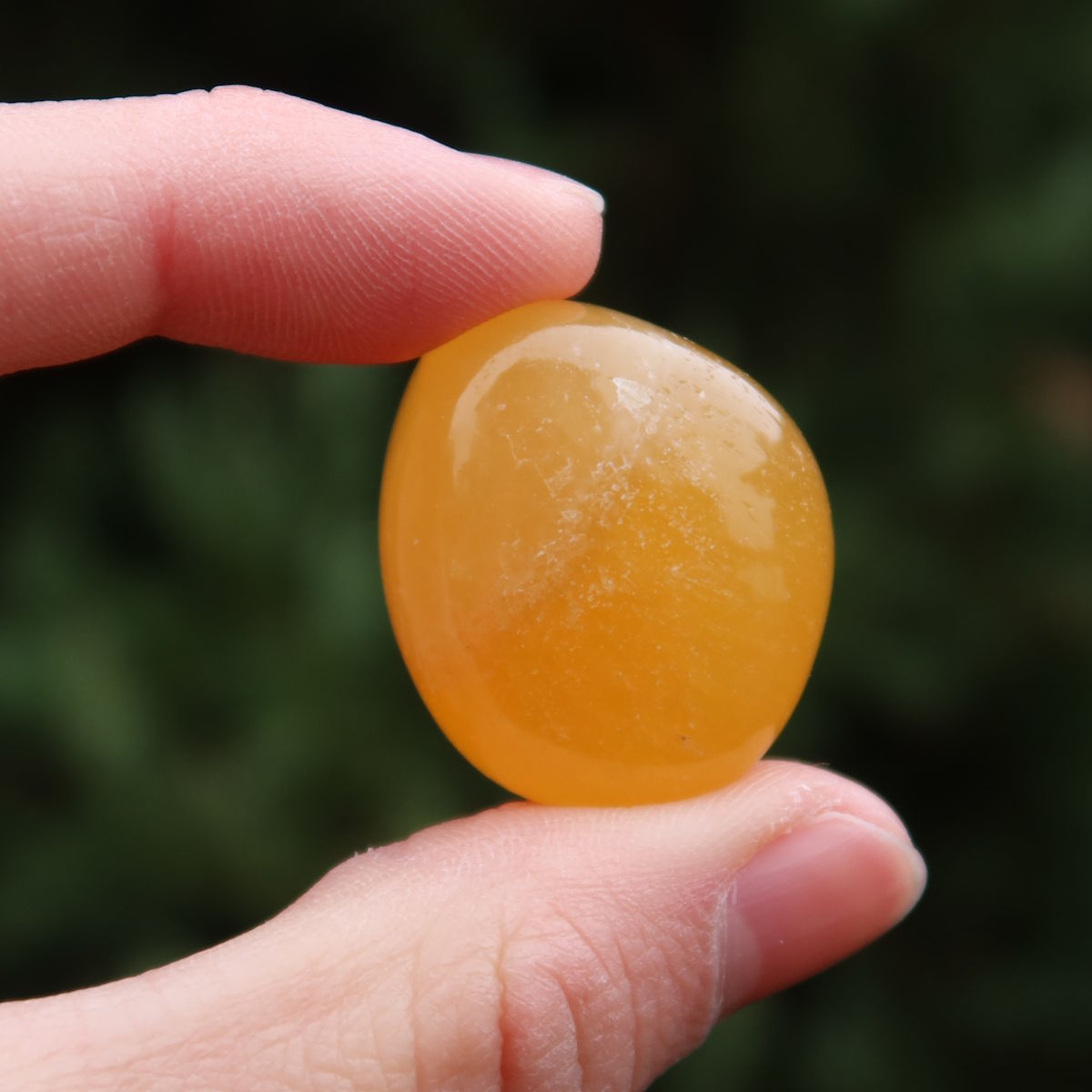 Calcit orange Handschmeichler - Selbstvertrauen und Positivität - Nr. 17 in der Hand, leuchtende orange Farbe.