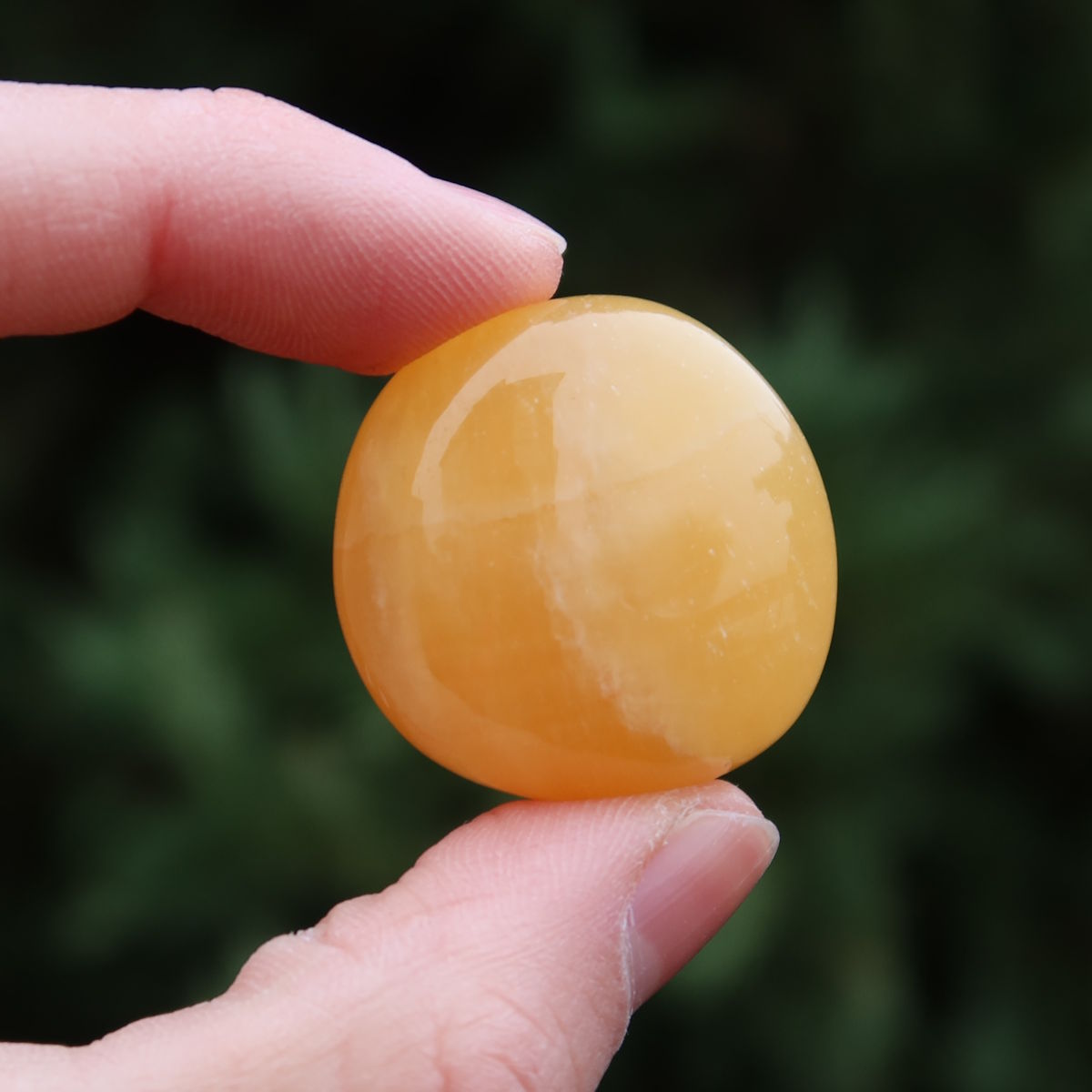 Calcit orange Handschmeichler - Selbstvertrauen und Positivität - Nr. 22 in der Hand, funkelnd und warm.