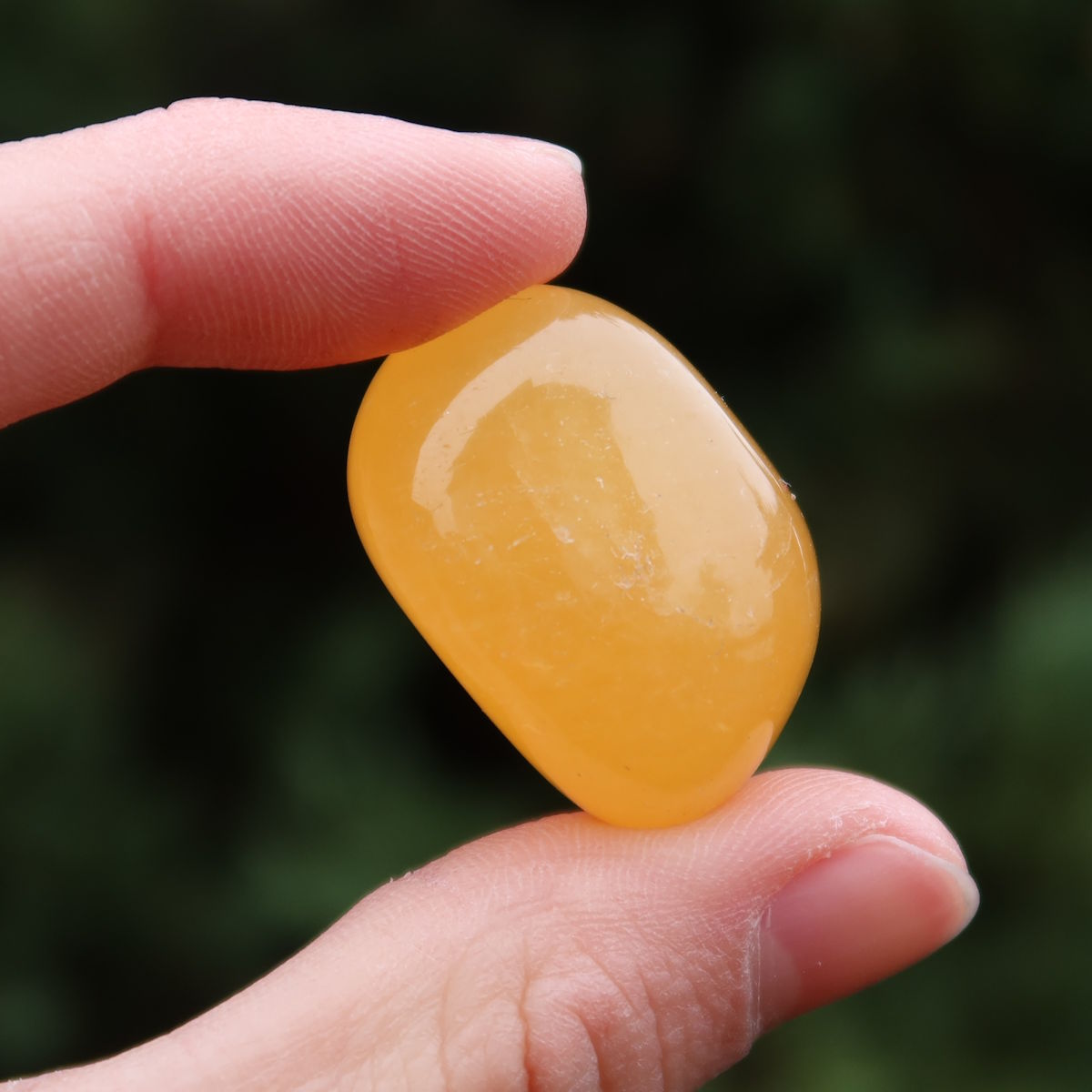 Calcit orange Handschmeichler - Selbstvertrauen und Positivität - Nr. 6 in Hand, strahlende gelbe Farbe.