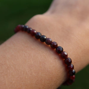Faceted Garnet Pyrope bracelet with deep red hues on a wrist, showcasing the elegant and energetic gemstone design.