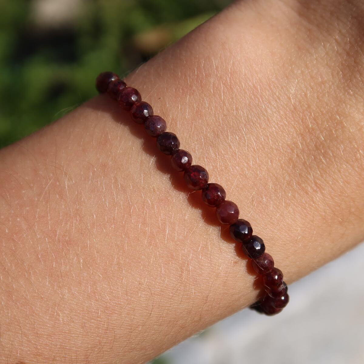 Faceted Garnet Pyrop gemstone bracelet in deep red tones, worn on wrist, showcasing elegance and energetic properties.