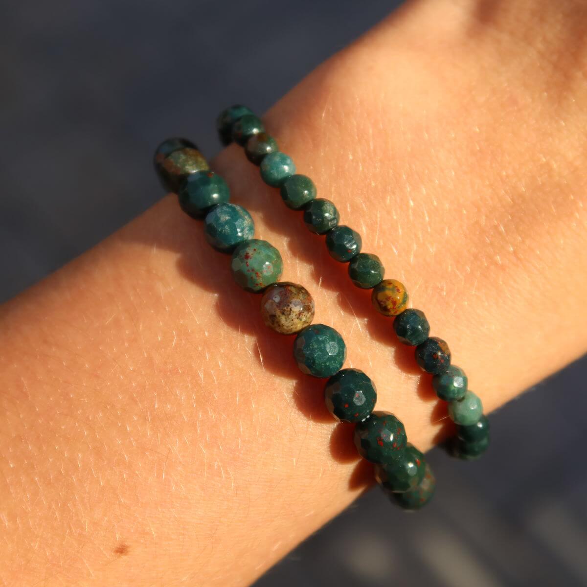 Faceted Heliotrop gemstone bracelets in green and red hues on wrist, highlighting vibrant colors and energetic properties.