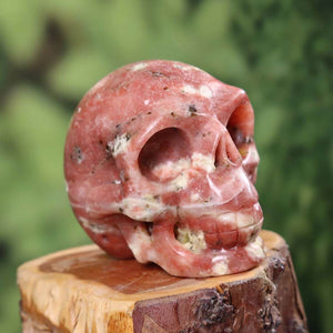 Handcrafted natural stone crystal skull with unique patterns on wooden base, collector's item, 7x6 cm.