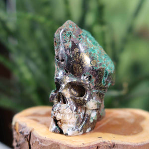Handcrafted Uvarovite Garnet Crystal Skull, unique shape, 5x6 cm, collectors' item on display, rich natural stone texture.