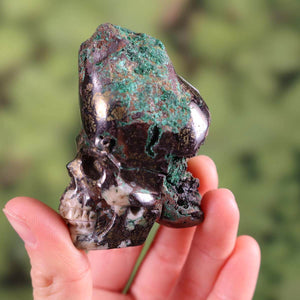 Handcrafted garnet uvarovite crystal skull, unique design, in a hand, 5x6 cm collectible piece.