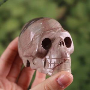 Handcrafted Jasper crystal skull with unique colors and shape, collector's item, 7x5 cm, held in hand against a green background.