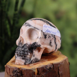 Handcrafted marble crystal skull, 7x5 cm, unique design with distinct patterns, displayed on wooden surface.