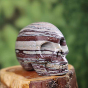 Handcrafted Printstone crystal skull, 7x6 cm, unique gemstone design, placed on wooden base, detailed carvings visible.