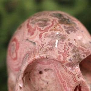 Nahaufnahme des Rhodochrosit Kristall Schädels XL, handgefertigt, zeigt einzigartige Muster und Texturen.