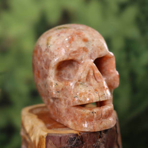 Handgefertigter Sonnenstein Kristall Schädel, Sammlerstück, 10x8 cm Größe auf Holzplattform.