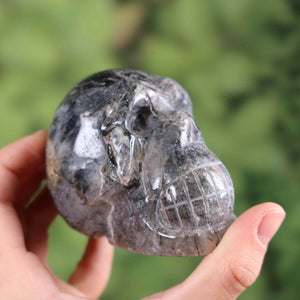 Handcrafted tourmaline quartz crystal skull with unique shape, held in hand, close-up view.