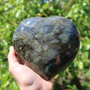 Labradorite heart gemstone in hand, showcasing unique blue and green iridescence, measuring 13x13x5cm, perfect for relaxation and creativity.