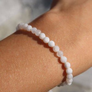 Faceted rainbow moonstone bracelet on wrist, displaying shimmering white beads with rainbow hues, jewelry accessory.