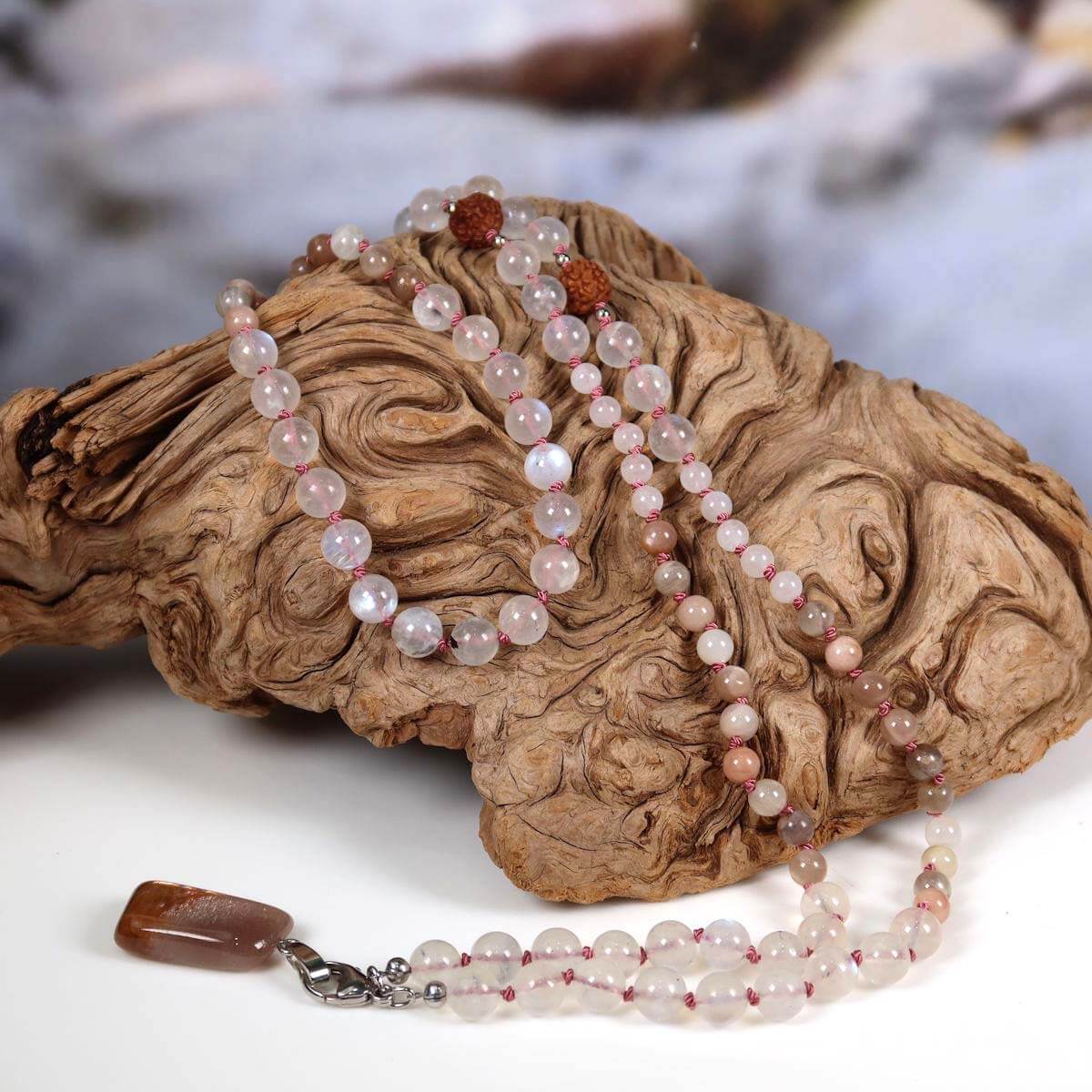 Handgeknüpfte Mala Kette mit Mondstein und Labradorit auf rustikalem Holz präsentiert