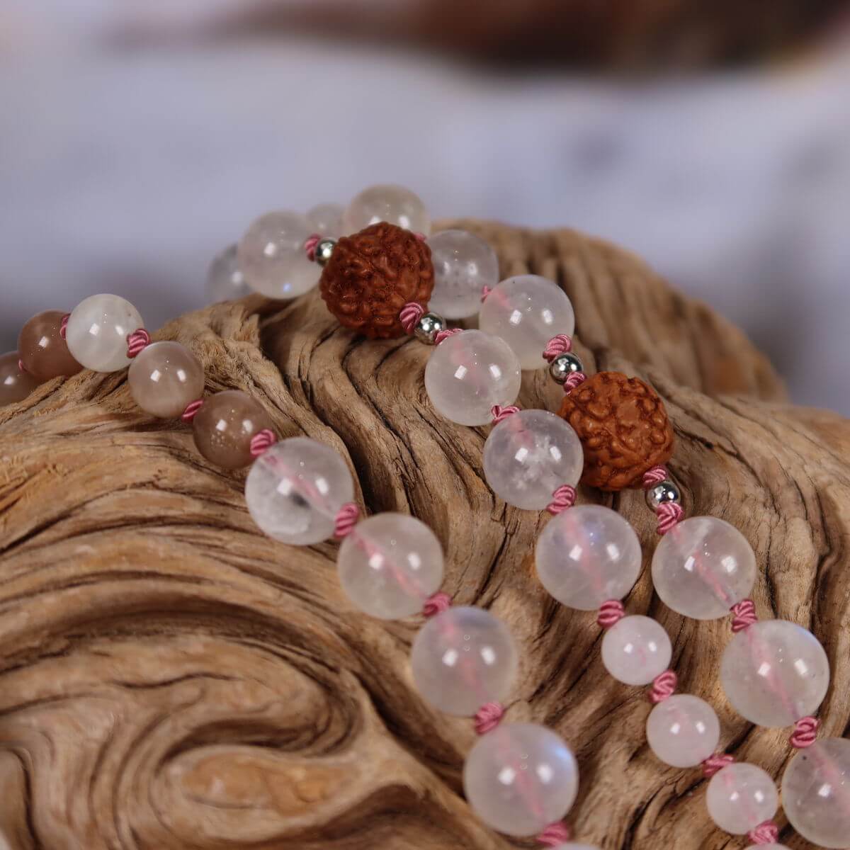 Handgeknüpfte Mala Kette mit Mondstein und Labradorit auf rustikalem Holz präsentiert