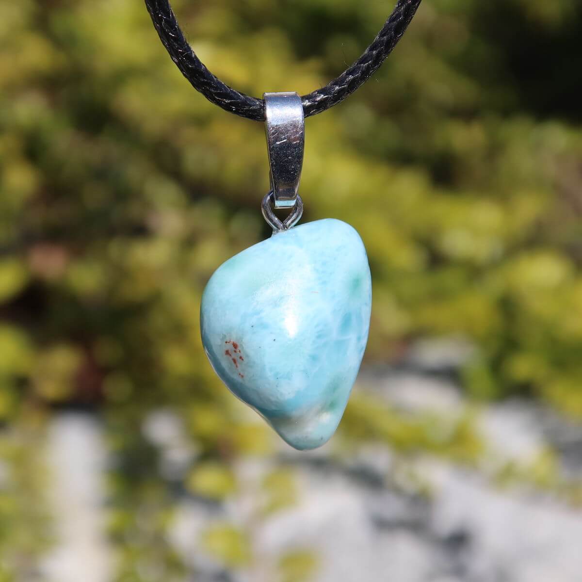 Larimar pendant with silver bail, 21mm in size, showcasing unique light blue color, set against a natural blurred background.