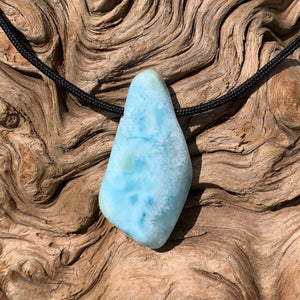 Larimar pendant against textured wooden background, unique 45mm gemstone jewelry from Dominican Republic.