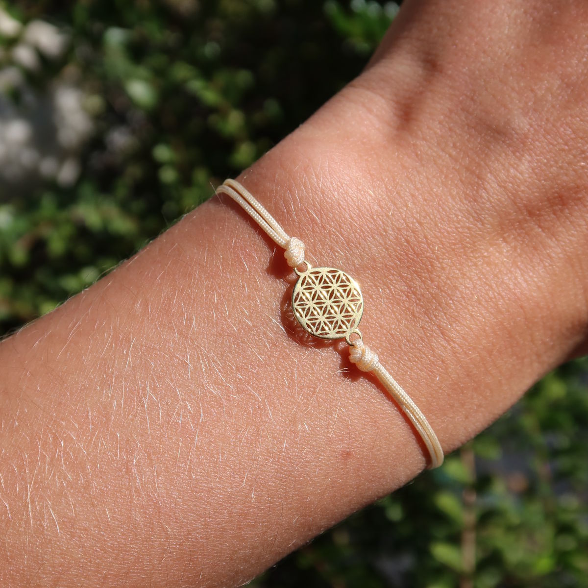 Makramee Armband mit Blume des Lebens vergoldet - Handgemacht und Größenverstellbar - Nr. 2, getragen am Handgelenk im Sonnenlicht.