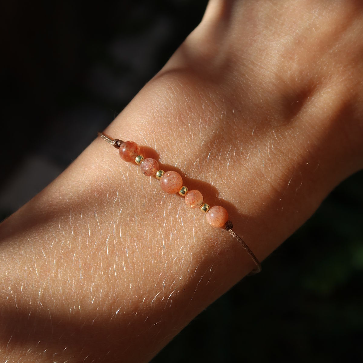 Handgemachtes Makramee Armband mit Sonnenstein - Lebensfreude und Selbstvertrauen - Nr. 6, funkelt im Sonnenlicht auf einem Handgelenk.