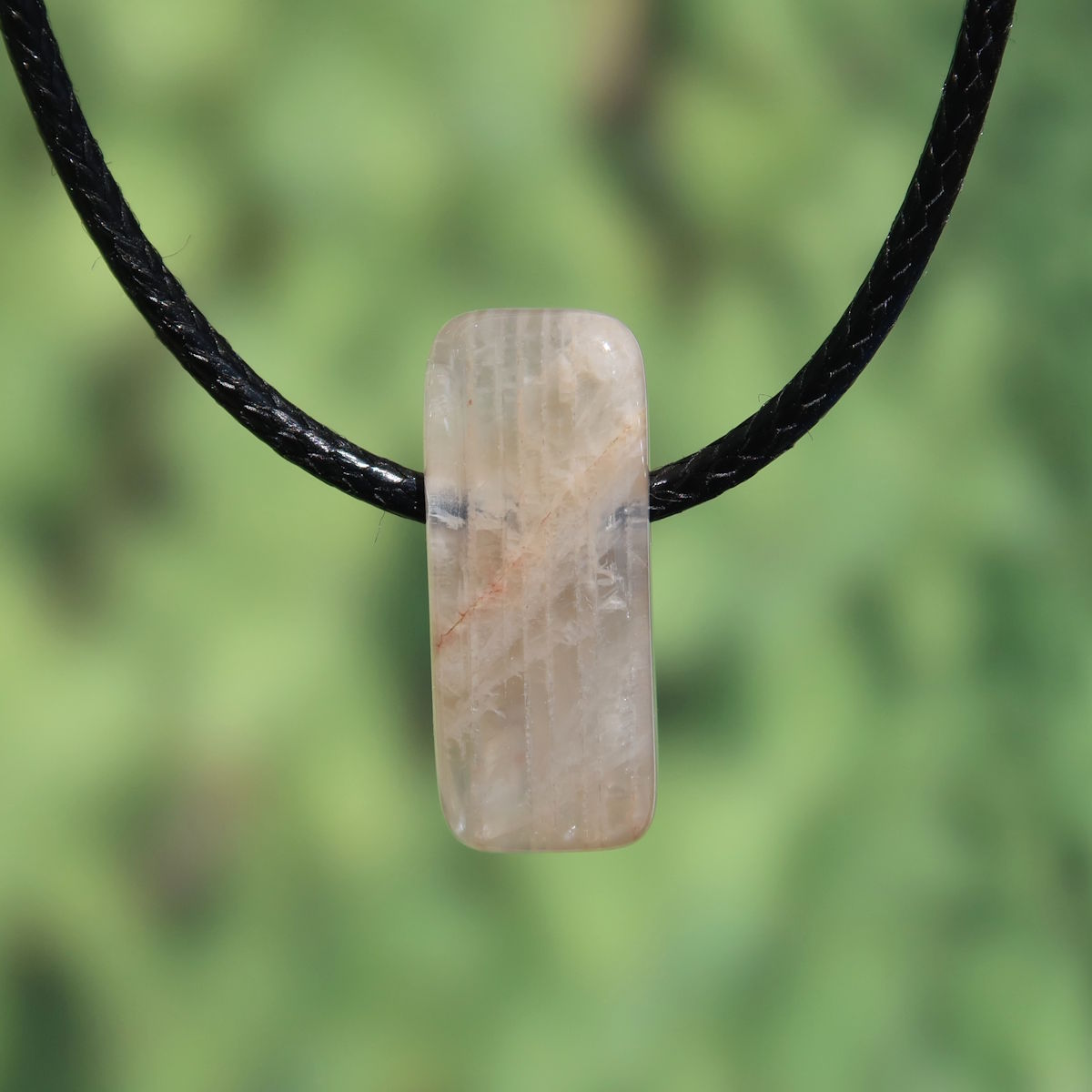 1A Qualität Mondstein weiß gebohrt - Weiblichkeit und Intuition - UNIKAT Nr. 4 Anhänger vor grünem Hintergrund