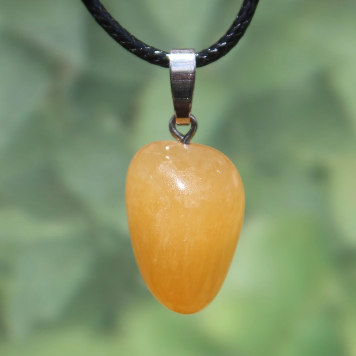 Calcit orange Anhänger - Selbstvertrauen und Positivität - Nr. 13 auf schwarzem Halsband, strahlend und warm.