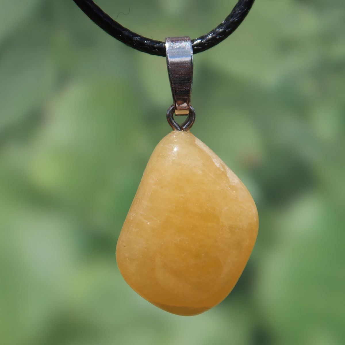 Calcit orange Anhänger - Selbstvertrauen und Positivität - Nr. 17 an einem schwarzen Halsband, strahlende Farbe.