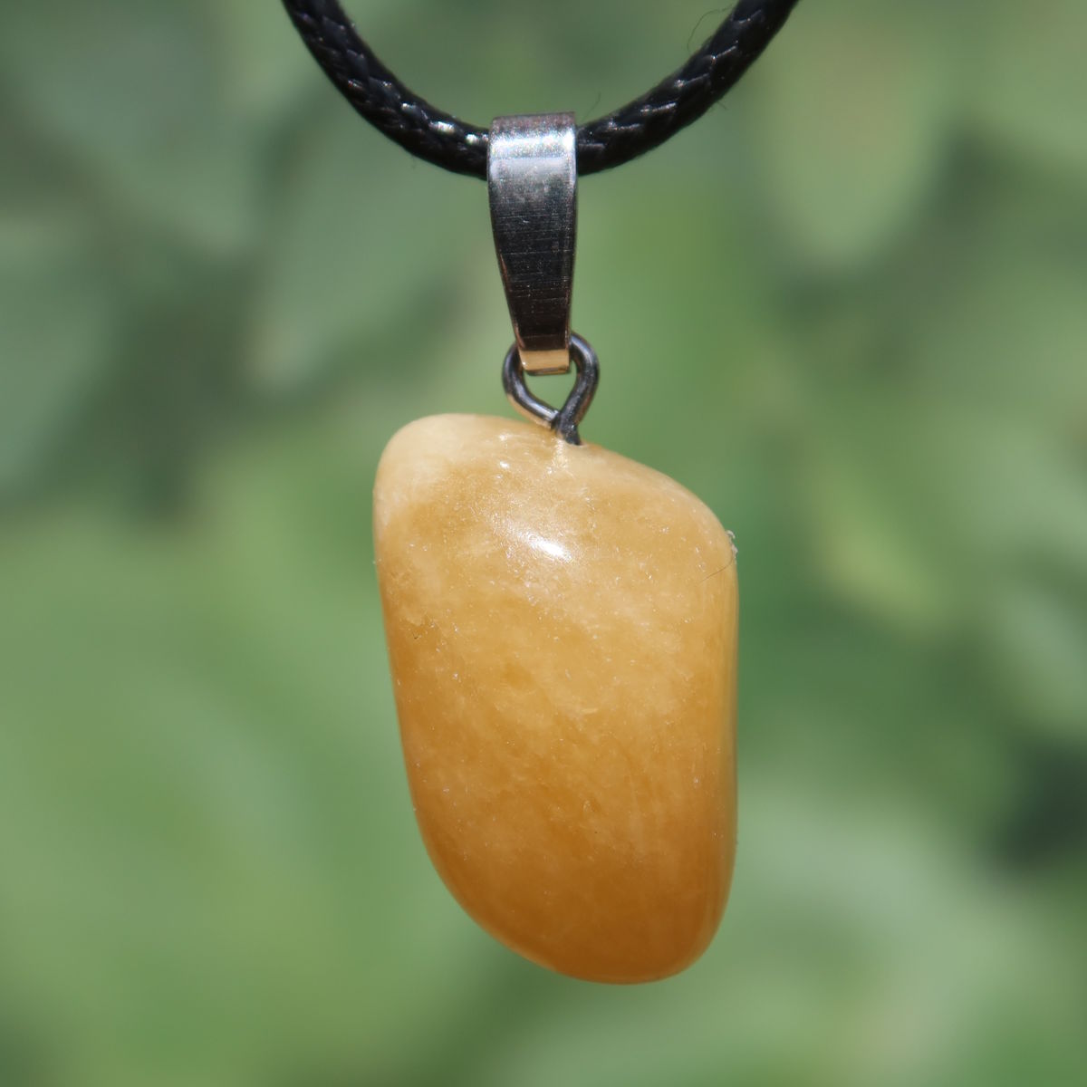 Calcit orange Anhänger - Selbstvertrauen und Positivität - Nr. 18 auf schwarzem Halsband, strahlend und warm.