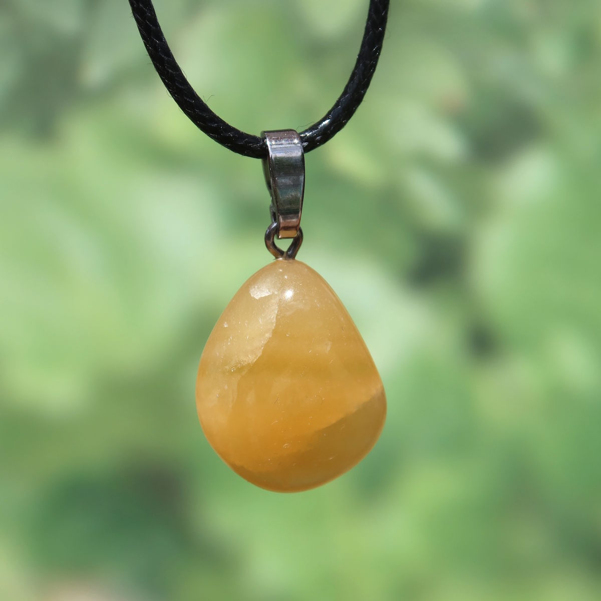 Calcit orange Anhänger - Selbstvertrauen und Positivität - Nr. 2 auf schwarzem Halsband, strahlend und warm.