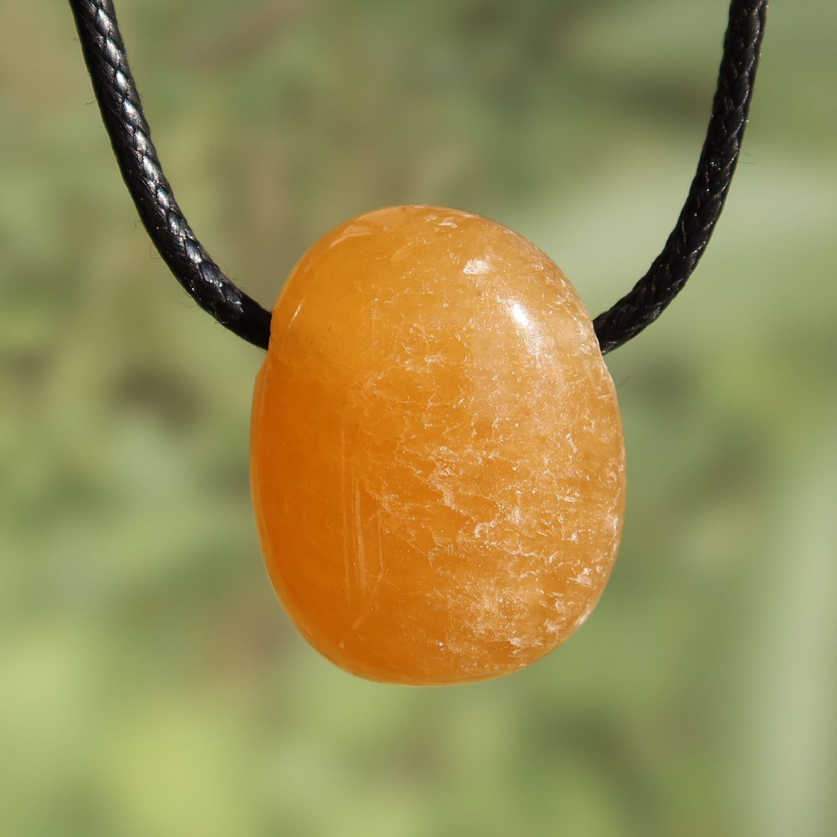 Calcit orange gebohrt - Selbstvertrauen und Positivität - Nr. 14, strahlender Anhänger mit warmen Orangetönen.