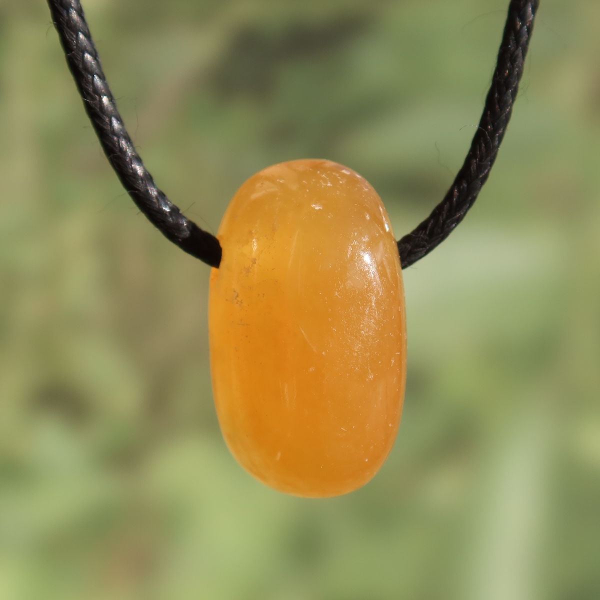 Calcit orange gebohrt - Selbstvertrauen und Positivität - Nr. 7 Anhänger in warmem Orange mit schwarzem Band.