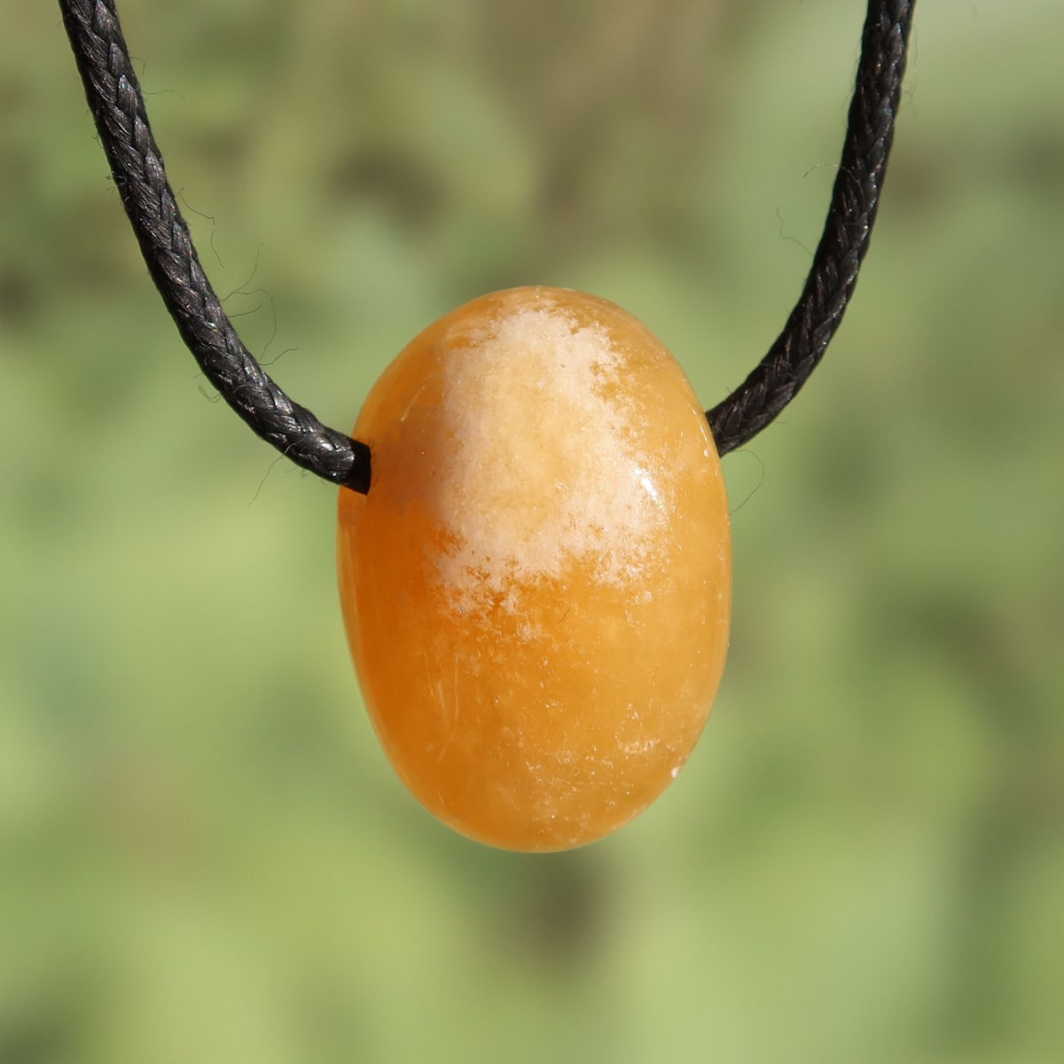 Calcit orange gebohrt - Selbstvertrauen und Positivität - Nr. 8 auf schwarzem Band, strahlende orange Farbe.